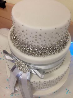 three tiered wedding cake with silver ribbons and bows