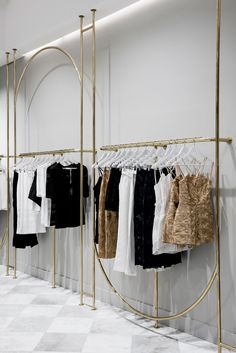 clothes hanging on racks in a clothing store with marble flooring and white tile floors