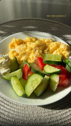 a white plate topped with eggs, cucumbers and tomatoes