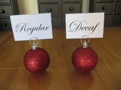 two red christmas balls with name tags on them sitting on a table next to each other