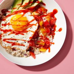 a white plate topped with rice covered in sauce and an egg