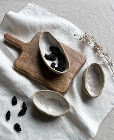 three spoons with dried blackberries in them on a white cloth next to some other items