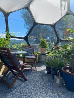 an outdoor area with chairs, tables and potted plants on the ground in front of a hexagonal window