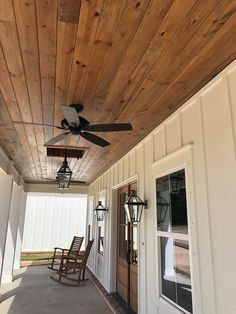 a ceiling fan on the outside of a house with wood paneling and white siding