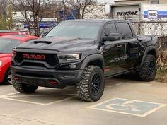 a large black truck parked in a parking lot next to other cars and trucks behind it