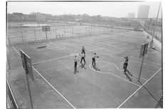 an old black and white photo of people on a basketball court with goal posts in the background