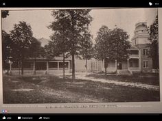 an old black and white photo of two houses in the middle of a field with trees