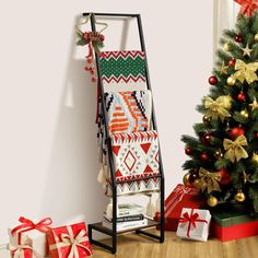 a christmas tree with presents under it next to a ladder