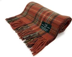 an orange and brown plaid blanket with a tag on the front, sitting on a white surface