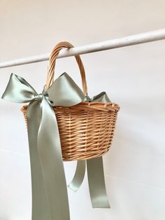 a wicker basket hanging on a clothes line with ribbons tied around the handles and ends