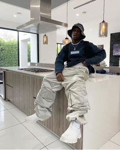 a man sitting on top of a kitchen counter next to a white tiled flooring