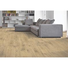 a living room with wood flooring and a gray couch in front of a bookshelf