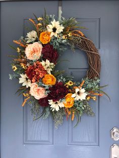 a wreath with flowers hanging on the front door