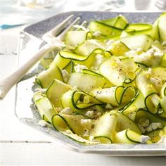 zucchini with cheese and herbs in a glass dish on a white wooden table