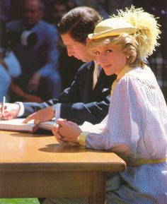 two people sitting at a wooden table writing