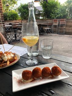 food and drinks on a wooden table in front of a glass of wine at an outdoor restaurant