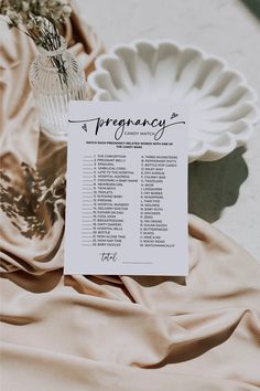 a table with a menu and vase on top of it next to a cloth covered tablecloth