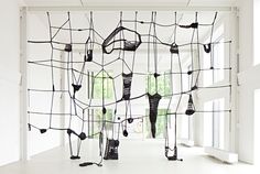 an art installation made out of wire and wires in a white room with large windows