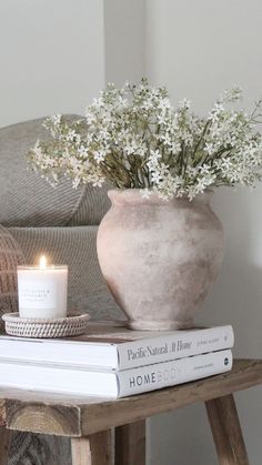 a vase filled with white flowers sitting on top of a table next to a book