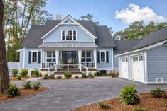 a blue house with white trim on the front and side windows, surrounded by trees