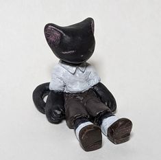 a small black cat sitting on top of a white floor next to a pair of shoes