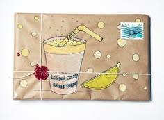 a wrapped package with a drawing of a drink and lemons on it, next to a postage stamp