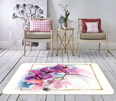 two chairs and a rug in a room with wood flooring, one has pink flowers on it