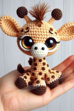 a small crocheted giraffe sitting on top of someone's hand