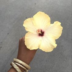 a person's hand with two bracelets and a yellow flower on their wrist