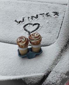 two cupcakes sitting on top of a car covered in snow