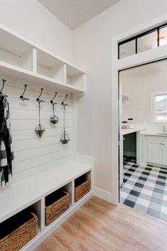 an entryway with white cabinets and black and white checkered flooring, hanging plants on hooks