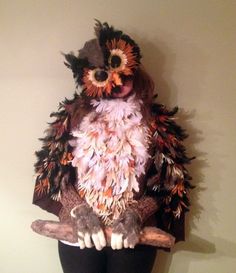 an owl made out of feathers sitting on top of a mannequin