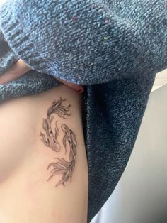 a woman with a tattoo on her stomach is looking down at the fish that are swimming in the water