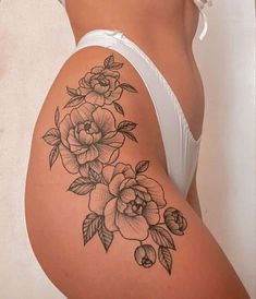 a woman's stomach with flowers on it and leaves around the waist, as well as an arm tattoo