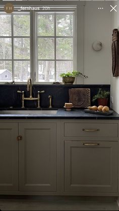 a kitchen with white cabinets and black counter tops, gold faucets on the sink