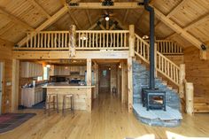 the inside of a log cabin with an open floor plan and wood burning stove in the center