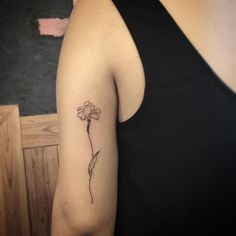 a woman's arm with a single flower tattoo on the left side of her arm