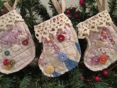 three christmas stockings hanging from a tree with buttons and crocheted lace on them