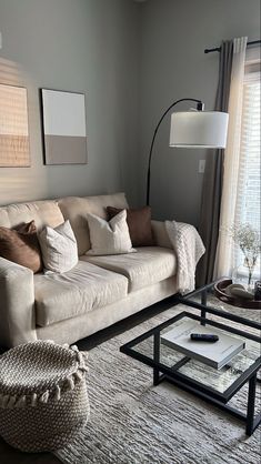 a living room filled with furniture and a lamp on top of a table in front of a window