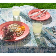 a pink plate topped with grapes and crackers next to a glass of milk on top of a table