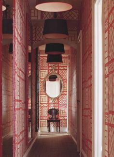 the hallway is lined with red and white wallpaper, along with a round mirror