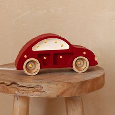 a red toy car sitting on top of a wooden stool