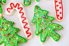 christmas cookies decorated with icing and sprinkles on a white tablecloth