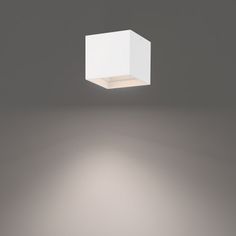 a square light that is on in the dark room with white walls and flooring