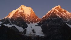 the snow covered mountains are illuminated by the sun's rays in the evening sky