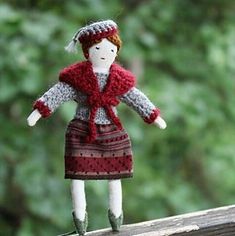 the doll is wearing a red and gray dress