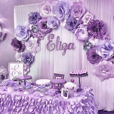 the table is covered with purple flowers and decorations for an elegant birthday party or baby shower