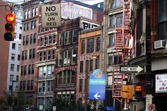 there are many tall buildings on this street with traffic lights and signs in the foreground