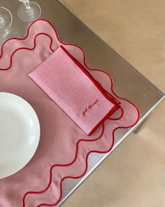 a place setting with pink napkins and wine glasses on a silver tableclothed tray