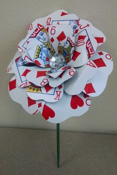 a flower made out of playing cards on top of a green stick with some candy in it